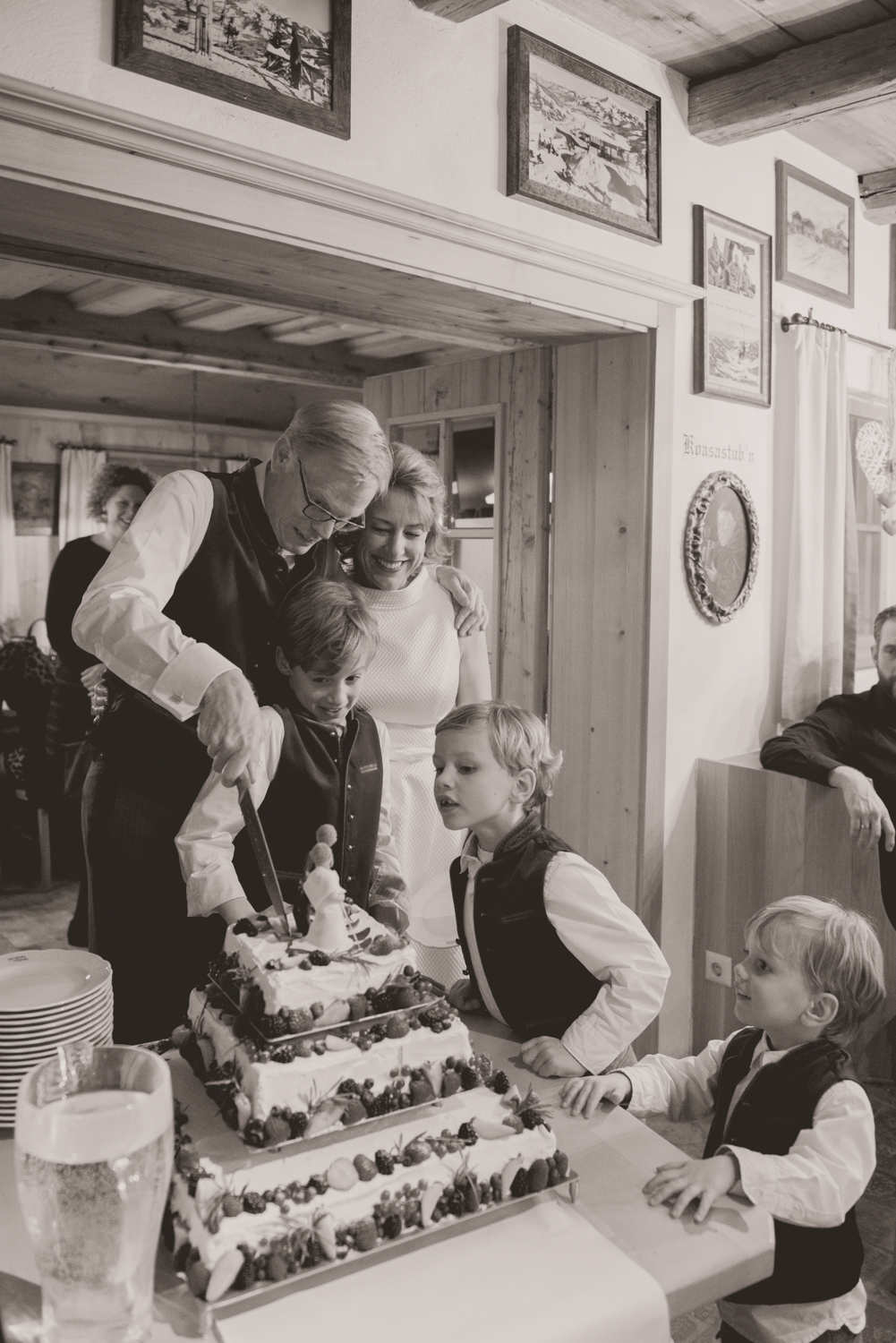 A bride, groom and their children cutting their ski themed wedding cake at their winter wedding in Austria