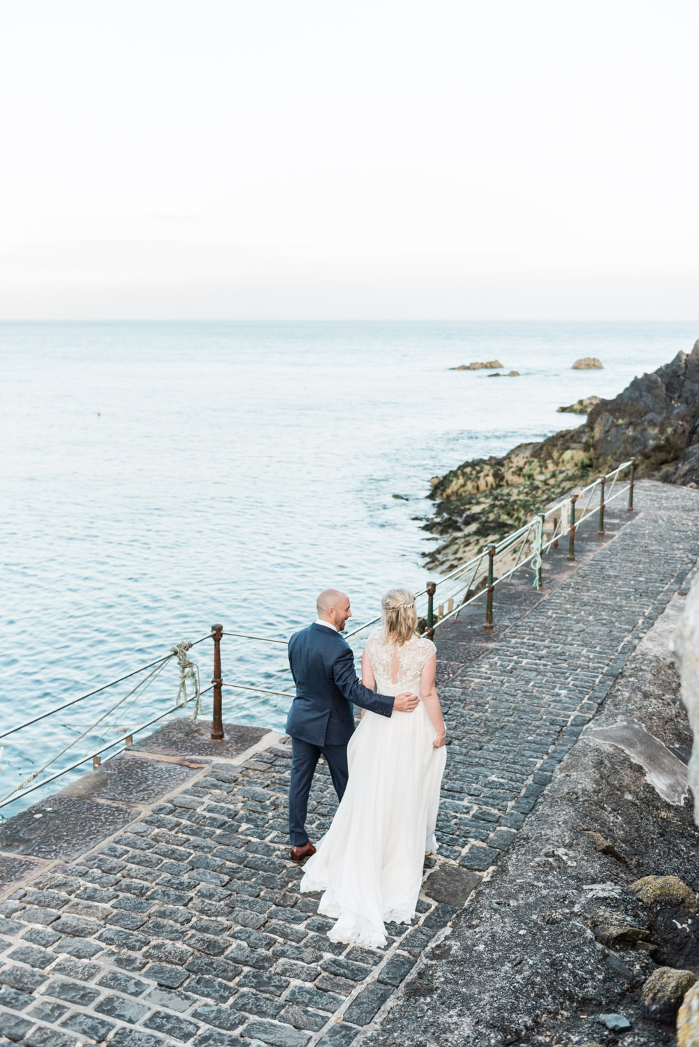 A bride and groom walking near Saint Bay Guernsey at their destination wedding, photographed by destination wedding photographer Wit Photography