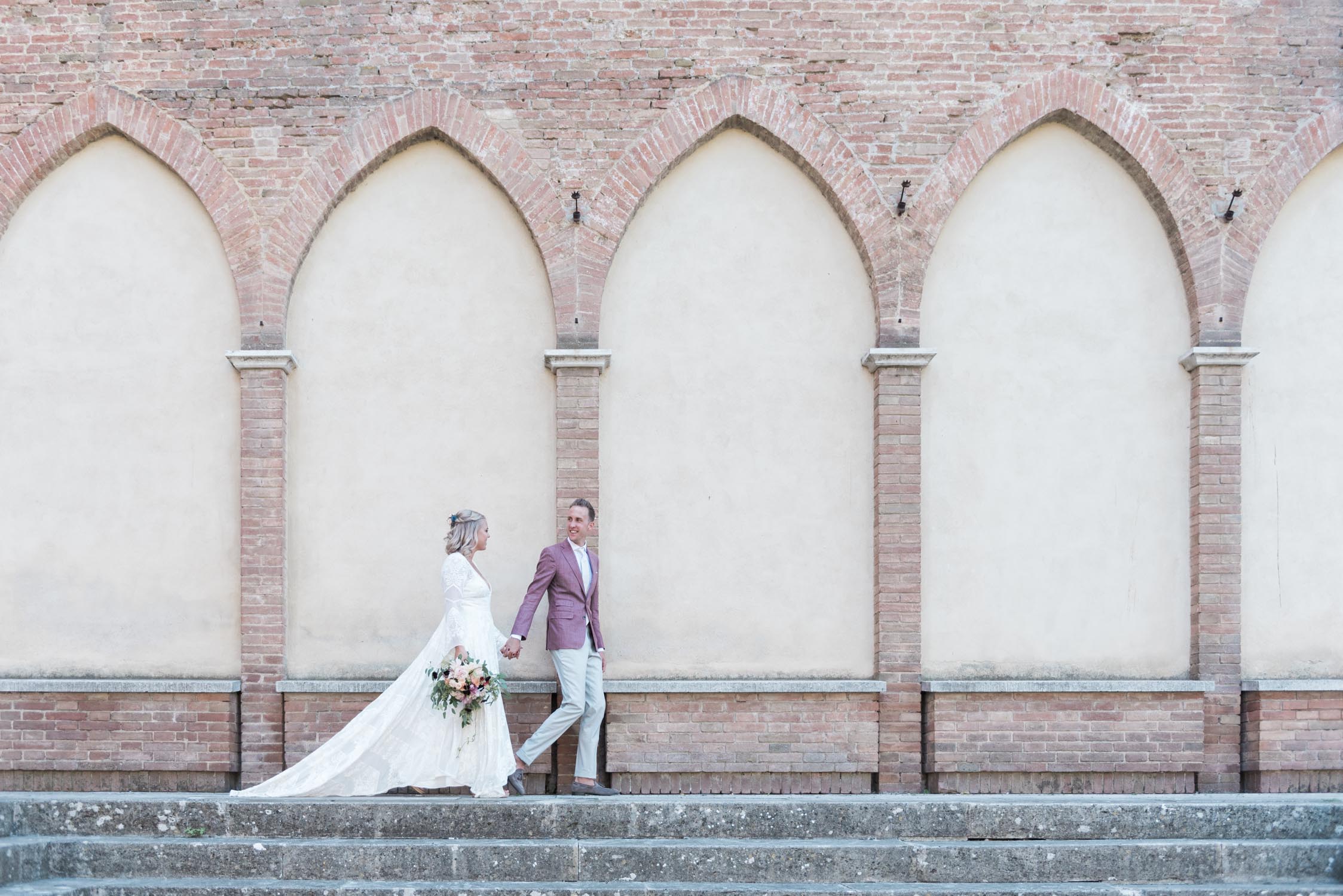 Bride and groom walking past a church in Siena, Tuscany, Italy