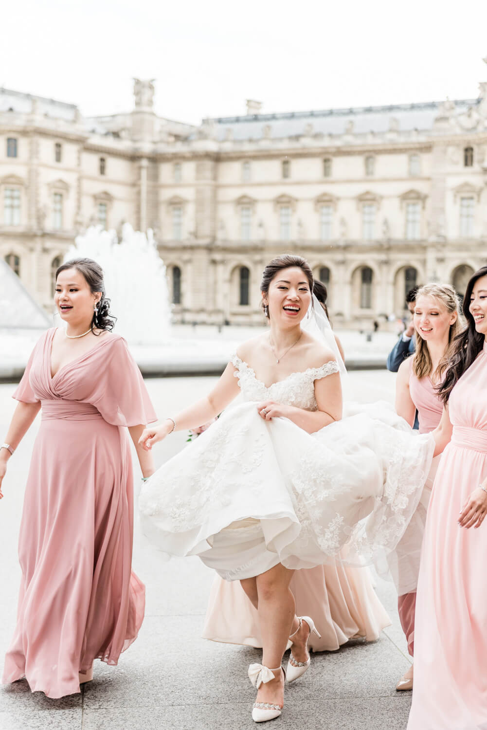 A bride and her bridesmaids walk at the Place du Louvre in Paris