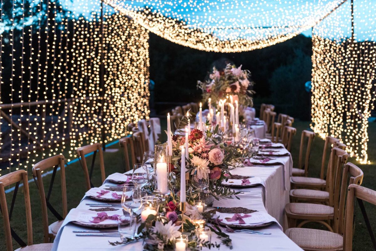 Flower abundant S shaped wedding table setting in a tunnel of light in Siena, Tuscany, Italy