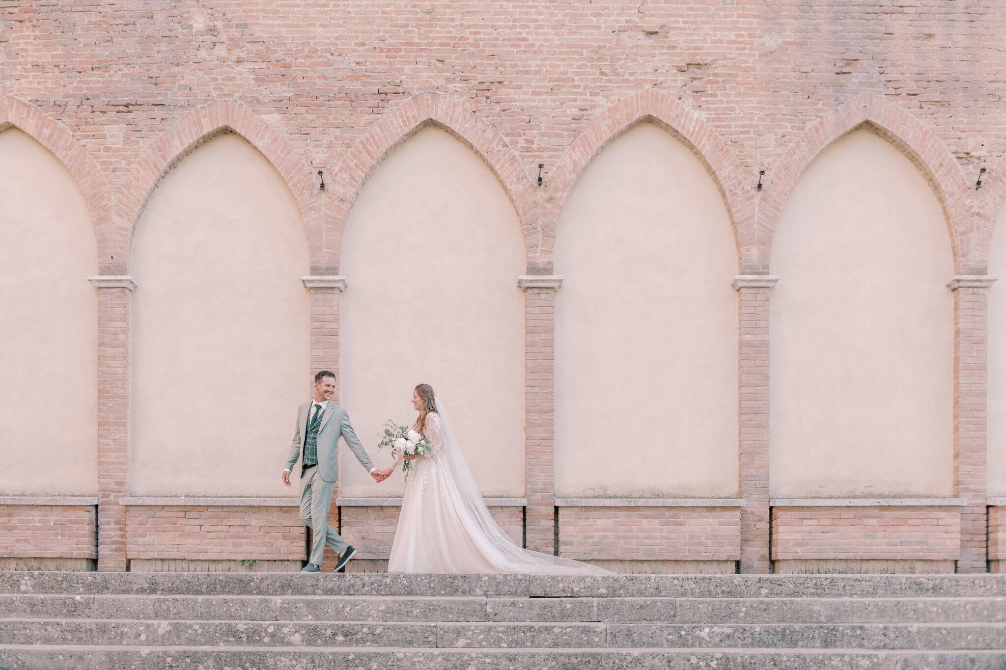 A bride and groom in front of a pink church as an illustration for a post about Dutch Wedding Traditions